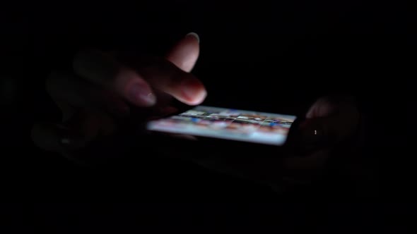 Close Up Woman Uses App on the Phone on the Black Background