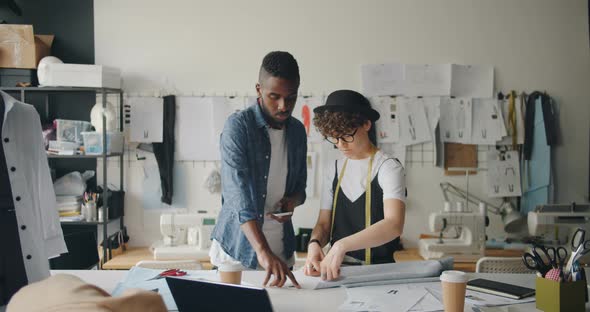 Fashion Designers Man and Woman Working with Fabric and Using Smartphone