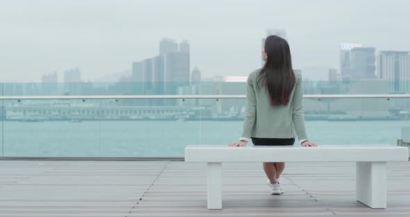 Woman sitting on bench and looking at the sea in Hong Kong