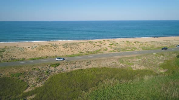 Cars Driving Along a Straight Coastal Road with Beautiful Sea Horizon in Sunny Day