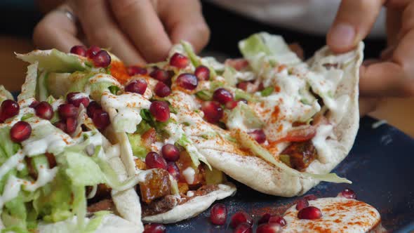 Close Up of Hands Picking on of Healthy Vegan Pita Stuffed with Veggies Under Vegan Mayo Sauce and