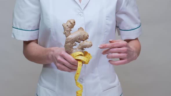 Nutritionist Doctor Healthy Lifestyle Concept - Holding Ginger Root and Measuring Tape