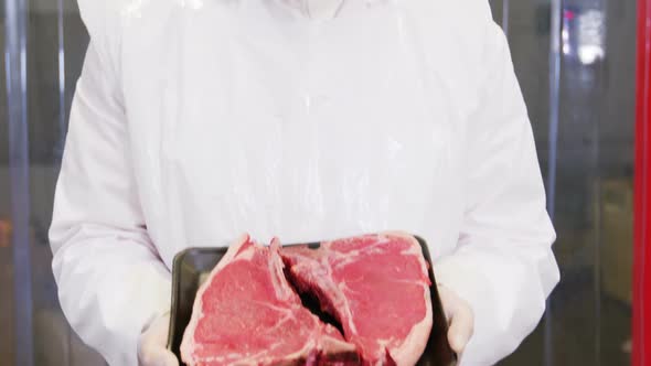Butcher holding a tray of raw meat