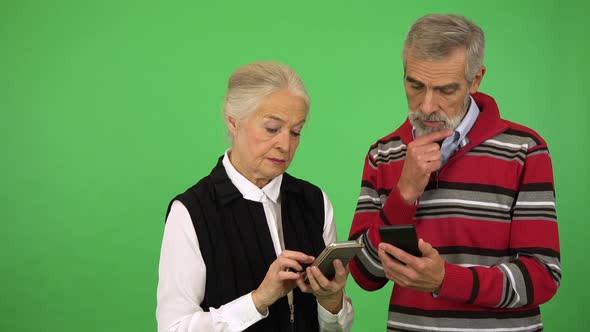 An Elderly Couple Works on Two Smartphones - Green Screen Studio