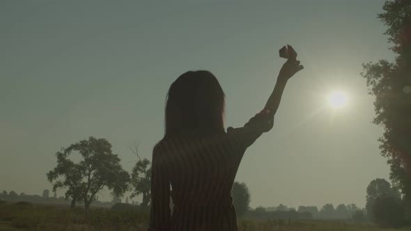 Rear View of Lovely African Female Playing with Paper Airplane at Sunrise