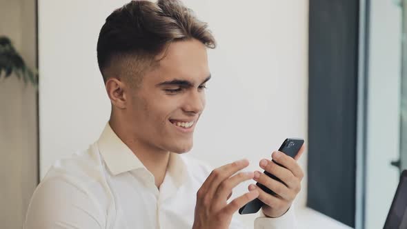 Young Happy Businessman Using Smartphone in Cafe, Steadicam Shot. Freelance, Communication, IT