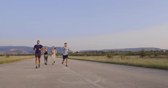 Multiethnic Group of Athletes Running Together on a Panoramic Countryside Road