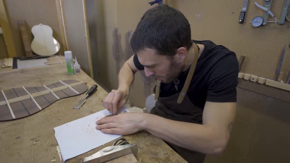 Craftsman flattening wooden piece with scraper in workroom