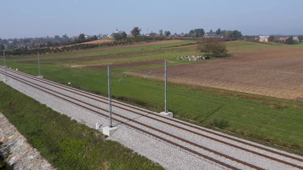 Aerial view of train tracks spanning through rural farmland in the Slovenian countryside near the vi