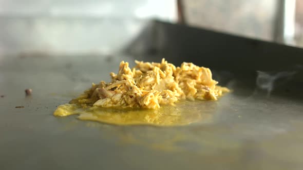 Pulled chicken being cooked on hot surface in restaurant