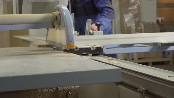 A man cuts a wooden slab on a format cutting machine.
