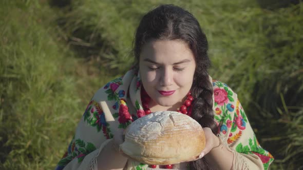 Portrait of Cute Overweight Woman Sitting in Grass Sniffing Tasty Bread Preparing To Eat