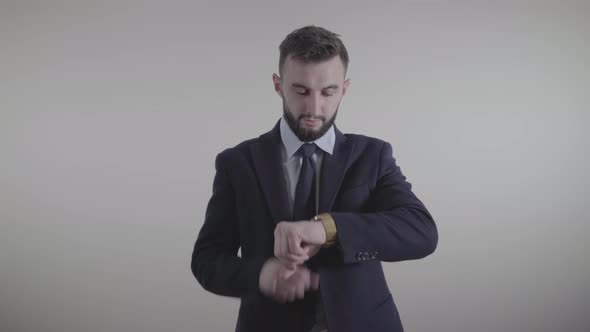 Portrait of Handsome Caucasian Businessman in Elegant Suit Looking at Time and Tapping on Watch Face