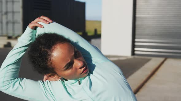 African american woman in sportswear stretching in street before exercising