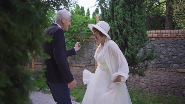 Cheerful Dance of Excited Married Senior Couple Outdoors in Spring Summer Park
