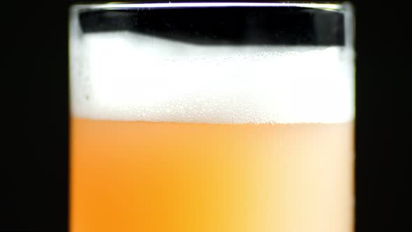 Extreme Closeup Craft Beer with Fluffy Foam and Air Bubbles in Transparent Mug Isolated Rotation