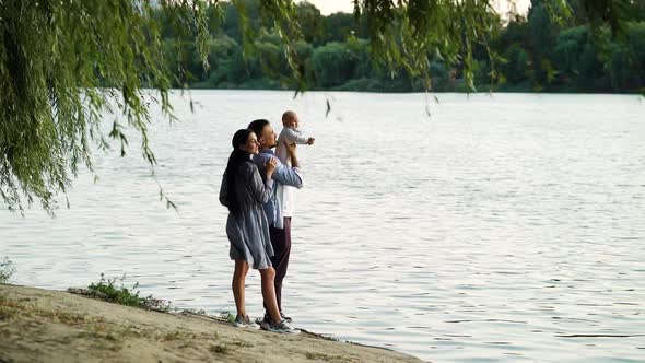 Loving parents with baby on bank of river