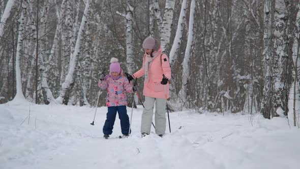 Girl with Mother Cross Country Skiing in Forest