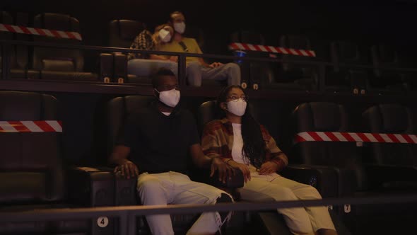 African Man and Woman Enjoying Film During Pandemic Wearing White Face Masks
