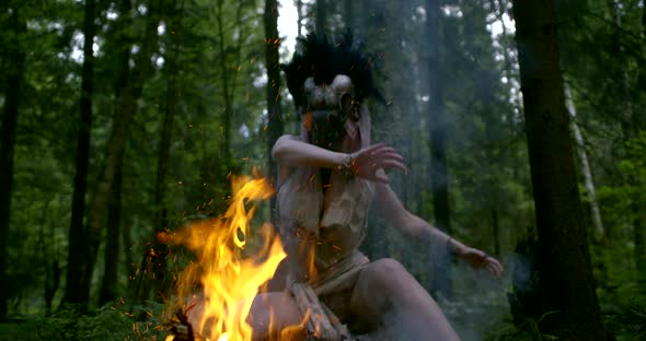 Mystic Lady in Mask Moves Hands Above Bright Orange Bonfire