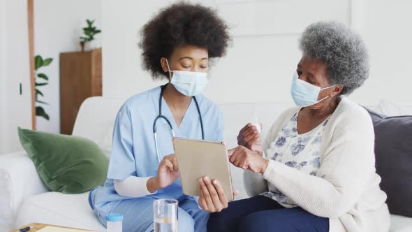 African american female doctor and senior female patient in face masks