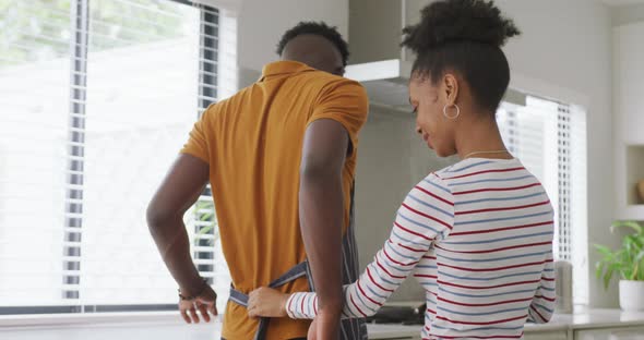 Video of happy african american woman tying apron to her partner