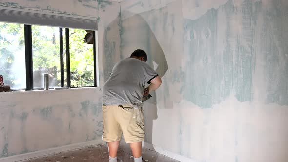 Man Aligning a Wall Working with Using Sand Trowel Sanding the Drywall