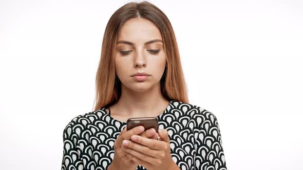 Upset Young Beautiful Blonde Girl Looking at Phone Over White Background