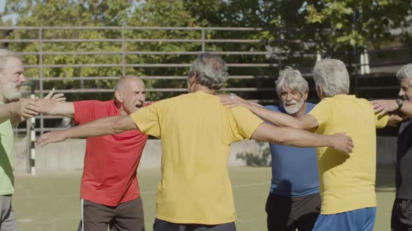 Cheerful Elderly Football Players Jumping in Circle Outside