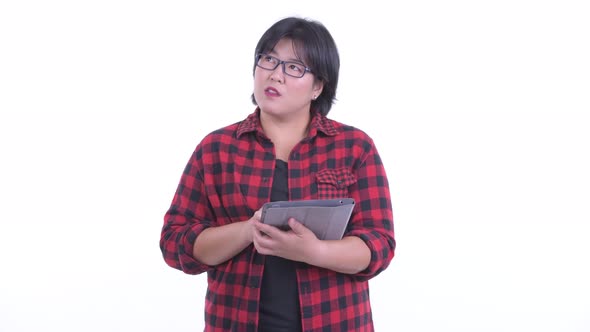 Happy Overweight Asian Hipster Woman Thinking While Using Digital Tablet