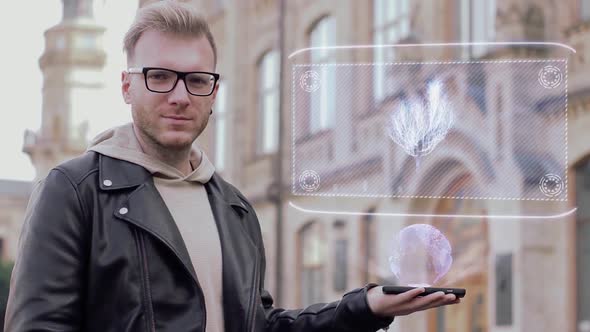 Smart Young Man with Glasses Shows a Conceptual Hologram Plant