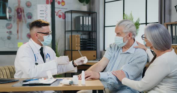 Male Worker Gives an Injection of a Vaccine or Some Medication to a Elder Man in the Clinic