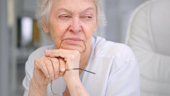 Thoughtful businesswoman with short grey hair puts head on hands