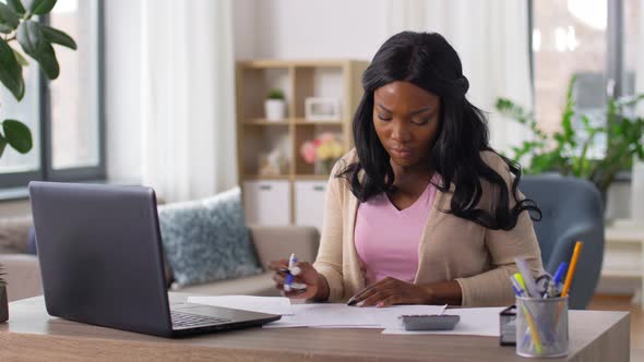 Woman with Calculator and Papers Working at Home