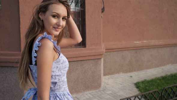 Slim European Model in Trendy Blue Dress Walks Along Street