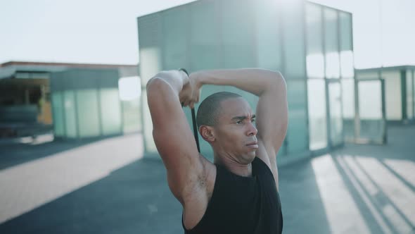 Bald sportsman wearing black T-shirt doing sport exercises with an elastic band