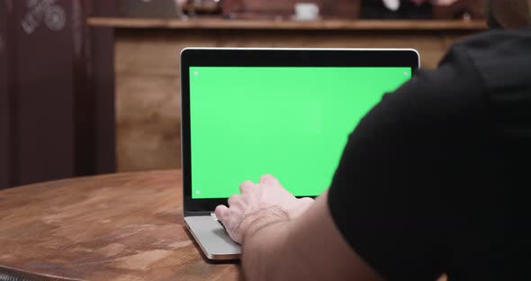 Revealing Shot of a Man Working on a Green Screen Computer