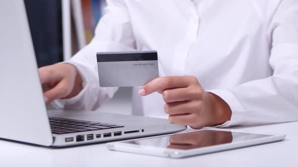 Girl Doing Online Shopping in Office in Front of Laptop with Gold Card. Close Up