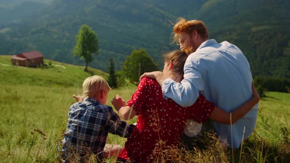 Loving Parents Hugging Sitting with Son on Mountain Hill