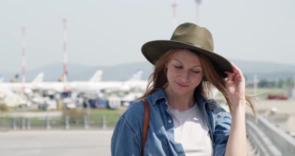 Happy tourist woman outside airport smiling and looking at camera.