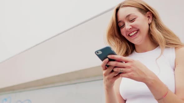 Young woman outdoor using smartphone laughing