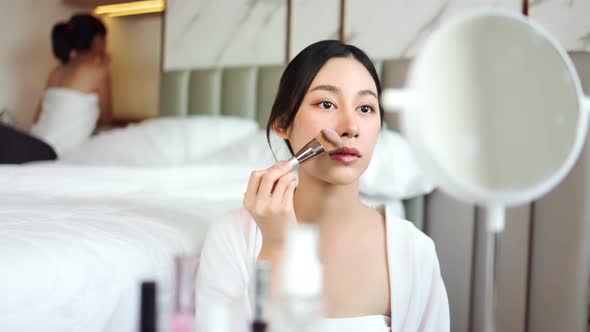 Happy attractive asian woman apply skincare cream on face and body.Female