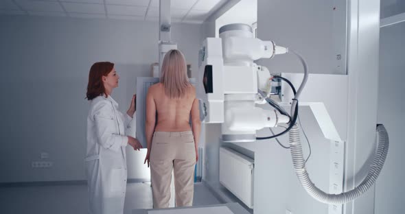 Mature Doctor Preparing Female Patient for Chest X Ray