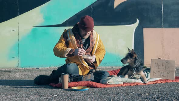 A Tramp and His Dog are Eating in City the Street