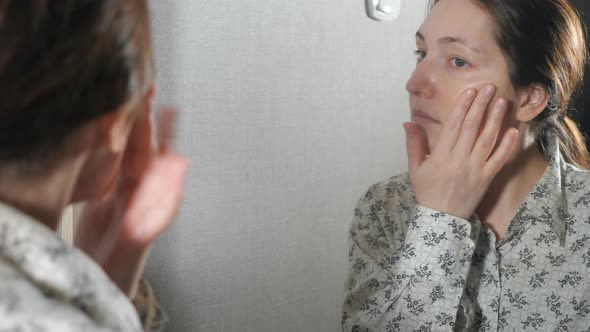 The Portrait of Young Woman with Skin Applying a Cream on Her Face