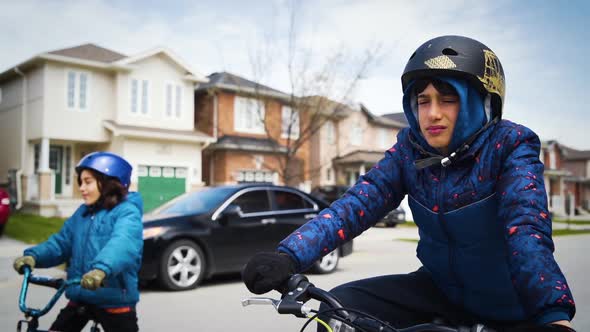 Two young boys riding bikes and staring into the distance