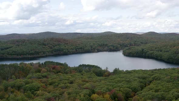 Picturesque lake in the setting of a large forest in the fall season - aerial view push forward