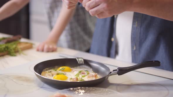 Unrecognizable Father and Son Putting Parsley on Fried Eggs