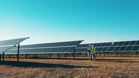 Drone Shot of Three Solar Energy Specialists Working on a Solar Farm