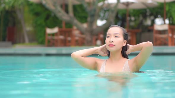 Young asian woman enjoy around outdoor swimming pool for leisure